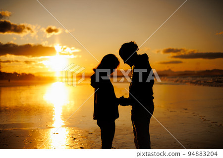 Silhouette of a couple holding their foreheads together at sunset Silhouette of a couple holding their foreheads together at sunset 94883204