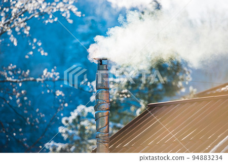 Smoke from the chimney on the roof 94883234
