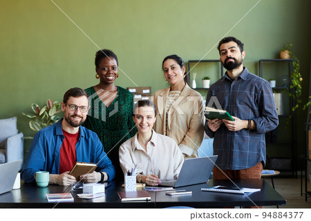 Team of young successful designers gathered by workplace looking at camera 94884377