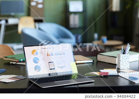 Laptop with financial diagrams and other data on screen standing on desk 94884422