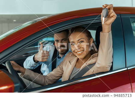 Young couple sitting inside new car and holding keys to it. Concept for car rental 94885713