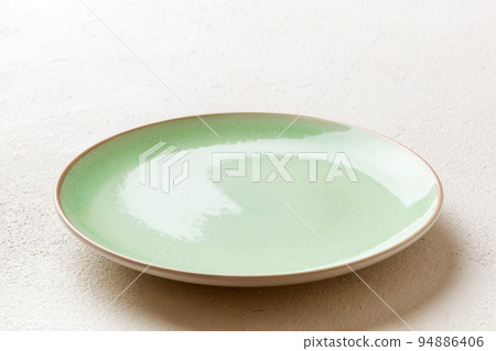 Perspective view of empty green plate on cement background. Empty space for your design Perspective view of empty green plate on cement background. Empty space for your design 94886406