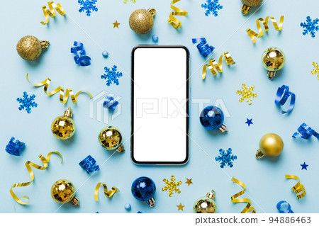 Christmas online shopping from home phone with blank white display top view. smart mobile with copy space on colored background with Christmas decorations balls,. Winter holidays sales background 94886463
