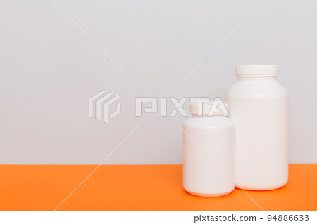 supplement pills with medicine bottle health care and medical top view. Vitamin tablets. Top view mockup bottle for pills and vitamins with green leaves, natural organic bio supplement, copy space 94886633