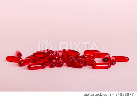 Heap of red pills on colored background. Tablets scattered on a table. Pile of red soft gelatin capsule. Vitamins and dietary supplements concept Heap of red pills on colored background. Tablets scattered on a table. Pile of red soft gelatin capsule. Vitamins and dietary supplements concept 94886877