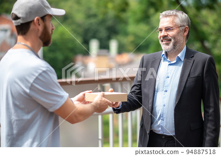 Mature businessman meeting the courrier from the delivery service Mature businessman meeting the courrier from the delivery service 94887518