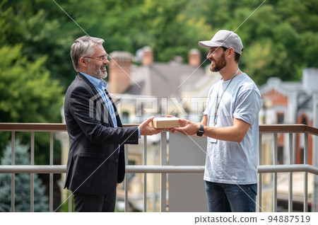 Mature businessman meeting the courrier from the delivery service 94887519