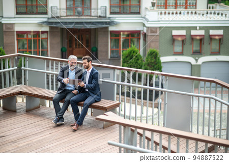 Business partners discuiing project details and looking involved Business partners discuiing project details and looking involved 94887522