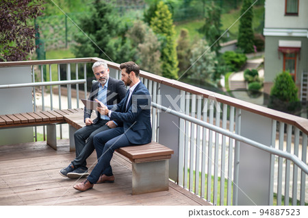 Business partners discuiing project details and looking involved Business partners discuiing project details and looking involved 94887523