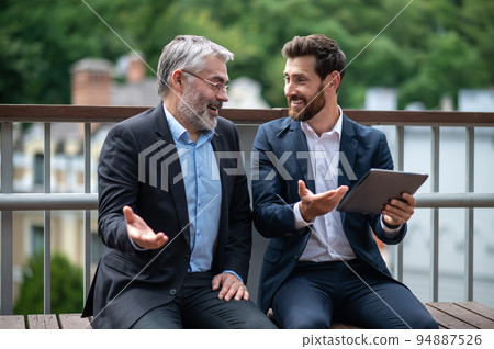 Business partners discuiing project details and looking involved Business partners discuiing project details and looking involved 94887526