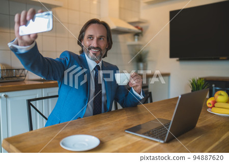 Good-looking mature man making selfie and smiling Good-looking mature man making selfie and smiling 94887620