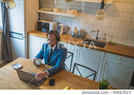 Man in blue suit having a vieo call and looking contented Man in blue suit having a vieo call and looking contented 94887623