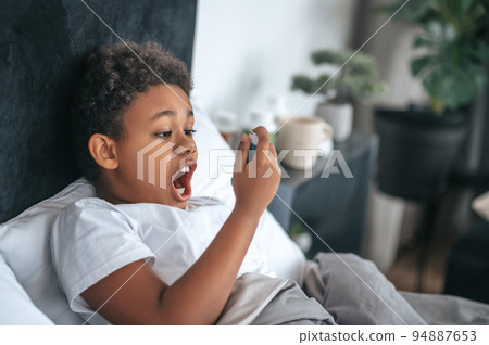 Sick boy having sore throat and spraying the remedy 94887653