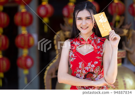 Portrait Asian young woman wearing red traditional Chinese cheongsam decoration holding yellow angpao envelopes with the Chinese text Blessings written on it Is a Good luck for Happy chinese new year Portrait Asian young woman wearing red traditional Chinese cheongsam decoration holding yellow angpao envelopes with the Chinese text Blessings written on it Is a Good luck for Happy chinese new year 94887834