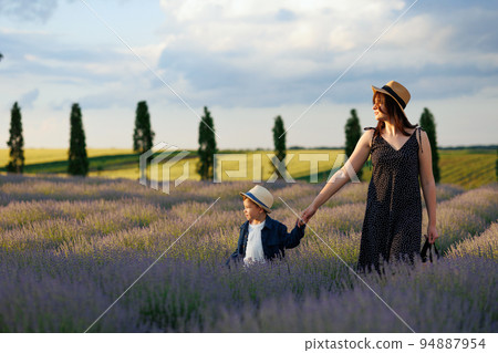 Mom and son watch the sunset while walking through the lavender field Mom and son watch the sunset while walking through the lavender field 94887954