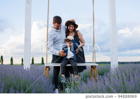 Happy family with son on swing in lavender field Happy family with son on swing in lavender field 94888069