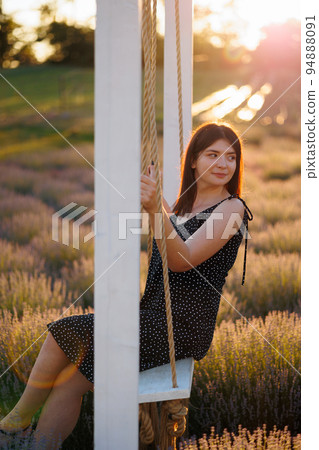 Girl on a swing in a lavender field at sunset Girl on a swing in a lavender field at sunset 94888091