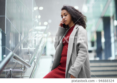 young woman talking on a mobile phone while standing in a subway tunnel. 94888324