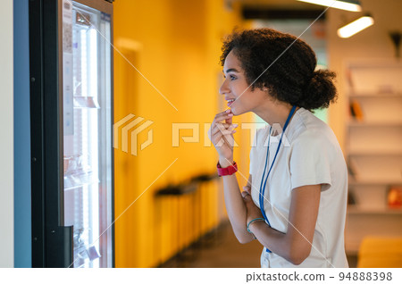 Young woman choosing something from the fridge in the office canteen 94888398