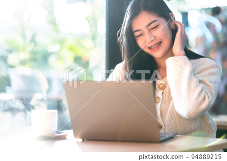 Portrait freelance business beautiful positive smile young asian woman online working with laptop computer and a coffee cup at home in the living room indoors or the cafe,Business Lifestyle 94889215