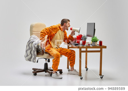 Young man in amazing costume shouting at megaphone at home. Colorful minimalism. Merry Christmas, New year holidays 94889389