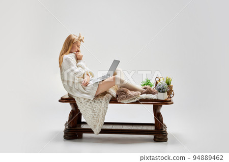 Young beautiful girl sitting at wooden table and using laptop isolated over grey background. Ideas, inspiration, imagination. Retro, vintage style Young beautiful girl sitting at wooden table and using laptop isolated over grey background. Ideas, inspiration, imagination. Retro, vintage style 94889462