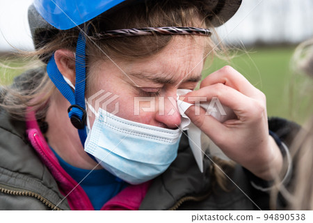 Tired girl with Down Syndrome and a bicycle helmet comforted by her friend 94890538