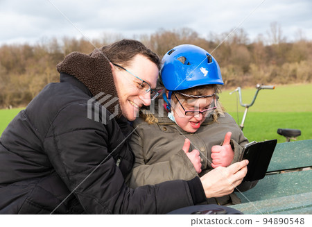 Girl with Down Syndrome communicating with her brother on a video call 94890548