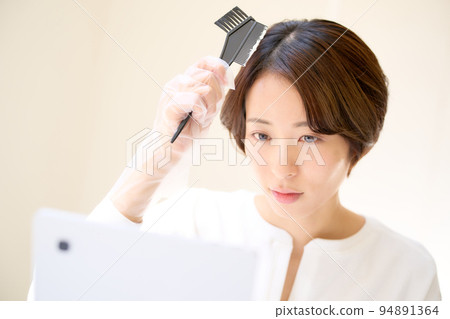 一個年輕女子在照鏡子時染髮自己的頭髮顏色圖像 94891364