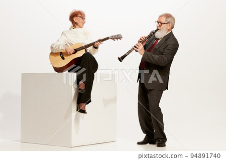 Musicians. Handsome senior man and charming middle age woman in vintage style autumn outfits isolated on white background. Concept of 60s, 70s fashion style 94891740