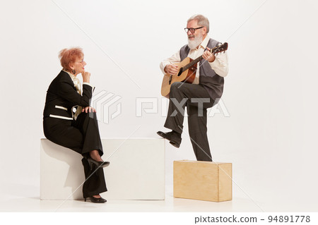 Serenade. Handsome senior man and charming middle age woman in vintage style autumn outfits isolated on white background. Concept of 60s, 70s fashion style 94891778