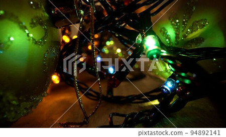 A sparkling transparent garland is carelessly wound into a heap. Christmas garland from the inside. Christmas burning garland close-up. A sparkling transparent garland is carelessly wound into a heap. Christmas garland from the inside. Christmas burning garland close-up. 94892141