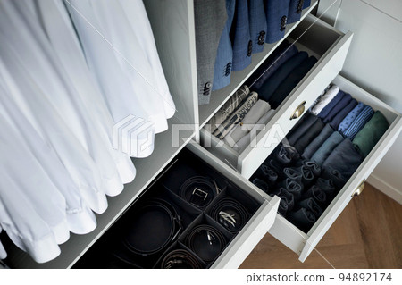 Man cupboard clothes storage organization neatly folded belt underwear shirt and socks 94892174