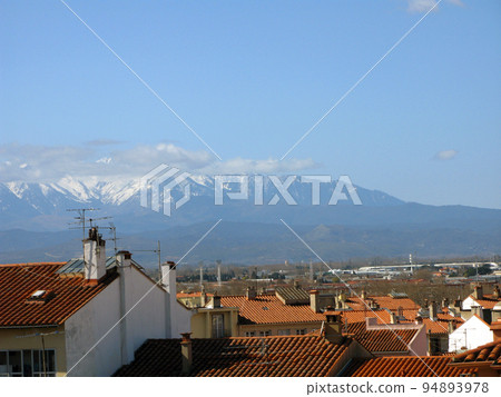 Perpignan. Panorama top view. Tiled roofs of houses and mountains with snowy peaks in distance. Spring.  France. 94893978
