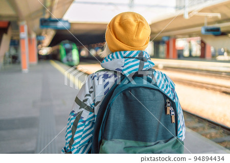Back view caucasian woman traveler with backpack in the railway Back view caucasian woman traveler with backpack in the railway 94894434