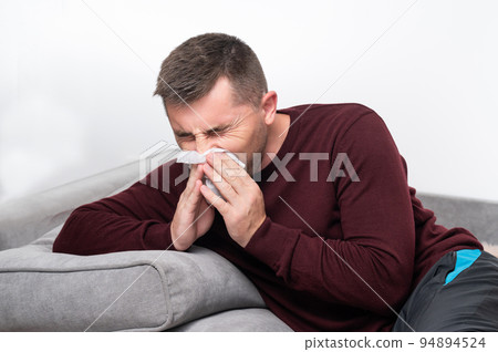 A weak and tired man blows his nose into a handkerchief. A weak and tired man blows his nose into a handkerchief. 94894524
