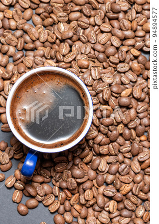 A cup of brewed black coffee on a dark background with beans. A cup of brewed black coffee on a dark background with beans. 94894577