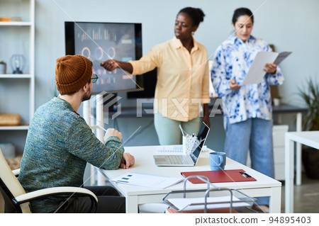 Young businessman sitting by desk with laptop and listening to coach Young businessman sitting by desk with laptop and listening to coach 94895403
