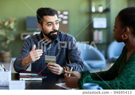 Confident businessman with color swatches explaining something to colleague 94895413