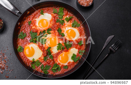 Shakshuka, a dish with fried eggs with tomato sauce, sweet pepper, garlic, onions, spices and herbs 94896987