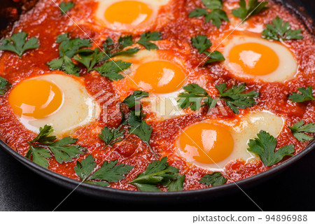 Shakshuka, a dish with fried eggs with tomato sauce, sweet pepper, garlic, onions, spices and herbs Shakshuka, a dish with fried eggs with tomato sauce, sweet pepper, garlic, onions, spices and herbs 94896988