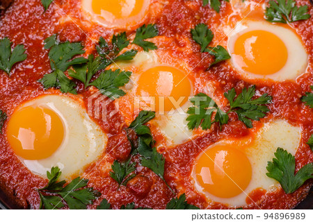 Shakshuka, a dish with fried eggs with tomato sauce, sweet pepper, garlic, onions, spices and herbs 94896989