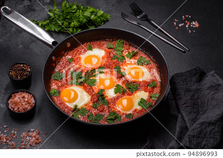 Shakshuka, a dish with fried eggs with tomato sauce, sweet pepper, garlic, onions, spices and herbs Shakshuka, a dish with fried eggs with tomato sauce, sweet pepper, garlic, onions, spices and herbs 94896993