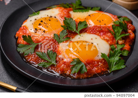 Shakshuka, a dish with fried eggs with tomato sauce, sweet pepper, garlic, onions, spices and herbs 94897004