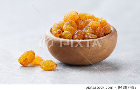 Pile of golden raisins on gray background 94897482