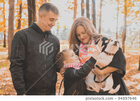 Family spend time in autumn park with a dog. Father, mother and daughter and jack russell terrier dog having fun in fall Family spend time in autumn park with a dog. Father, mother and daughter and jack russell terrier dog having fun in fall 94897646