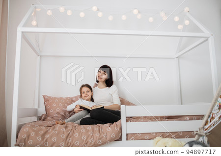 Caucasian preschooler girl and her young lady mother reading funny interesting children book 94897717