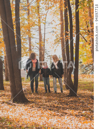 Grandmother and mother with granddaughter walks together in autumn park and having fun. Generation, leisure and family concept. 94897718
