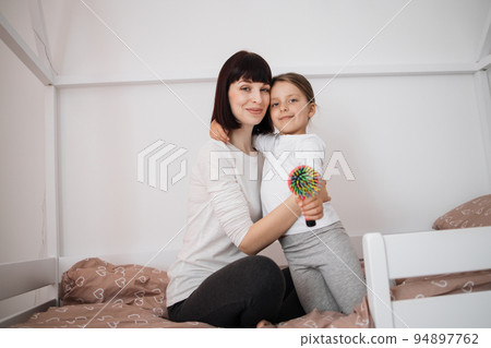 Satisfied caucasian young lady embracing preschooler girl after combing her hair 94897762