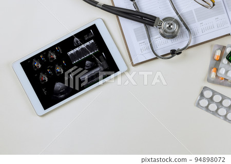 There is a doctor on the digital tablet who checks the results of echocardiography ultrasound in order to prescribe an effective treatment plan for the patient 94898072